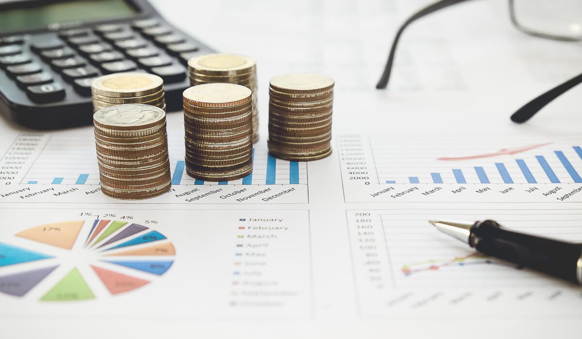 coins, calculator, glasses and graphs on table