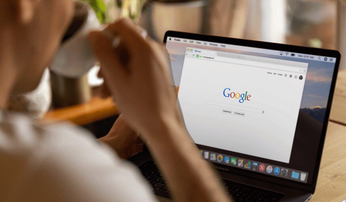 man drinking coffee, laptop in front of him with google on the screen