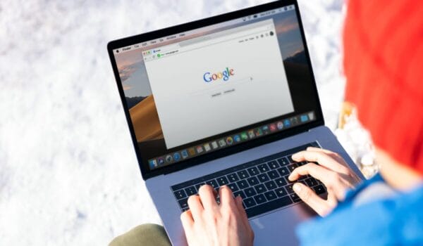 man typing on laptop, google homepage on screen