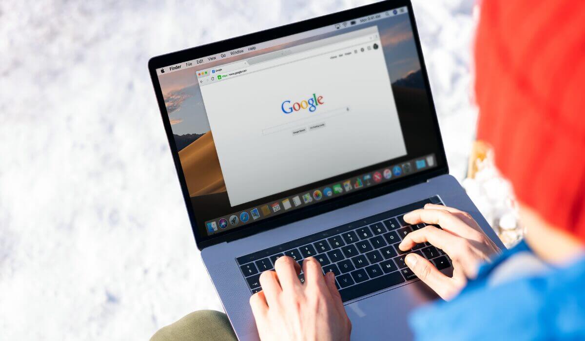 man typing on laptop, google homepage on screen